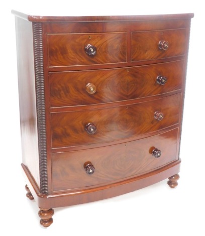 A Victorian figured mahogany bowfronted chest of drawers, with a plain frieze above two short, three long drawers, each with turned wood handles, flanked by gadrooned corners, on bun feet, 105cm wide.