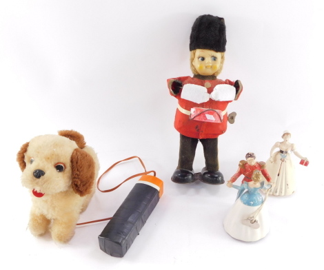 A Jamina remote control soft toy dog, clockwork tin plate and rubber guardsman and drummer, clockwork Cinderella and Prince Charming figure, and a further clockwork figure. (4)