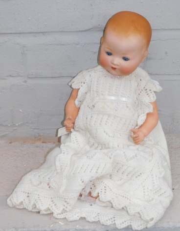 A German bisque porcelain doll, stamped AM Germany, and numbered 351-3-2K, on papier mache body, in knitted night dress.