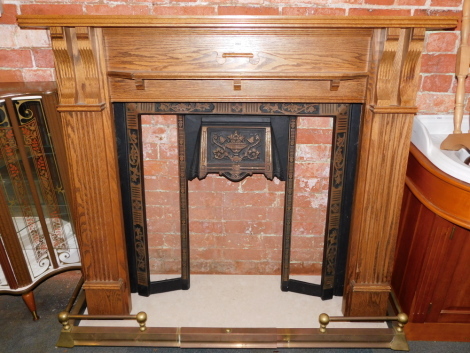 An oak fire surround, with cast iron inset, lacking tiles, with marble base, and brass fender. (4)