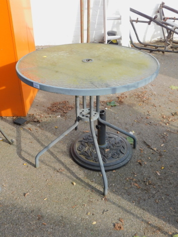 A metal garden table with glass top, together with a cast metal parasol stand. (2)