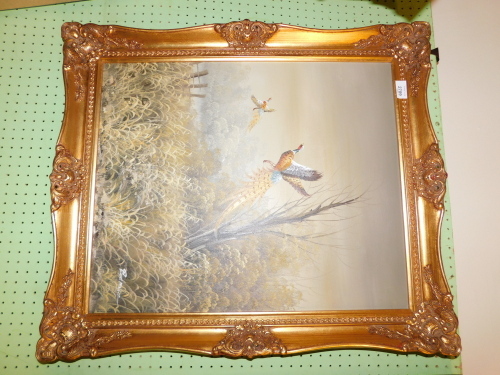 An oil on canvas by Redmond of pheasants in flight, gilt framed.