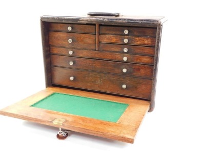 A Neslein 1940's oak engineer's cabinet, of rectangular section with a carrying handle, the drop flap opening to reveal an arrangement of five short and three long graduated drawers, with key, 33cm high, 46cm wide, 22cm deep. - 2