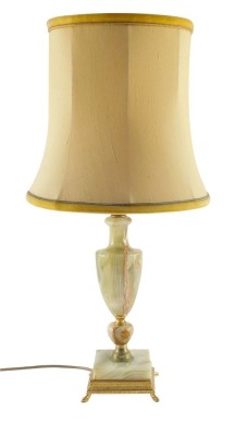 An onyx and brass table lamp, of baluster vase shape form, raised on a square base, with shade, 63cm high.