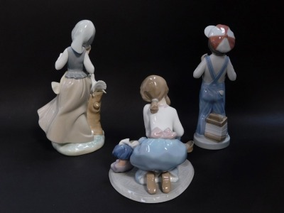 Three Lladro porcelain figures, comprising a kneeling girl with doll and ironing board, standing girls with doves, and a boy in dungarees with an accordian. - 2