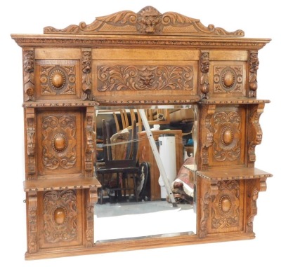 A Victorian oak overmantel mirror, the pediment carved with the head of a lion and foliate scrolls, above a rectangular bevelled glass mirror surmounted and flanked by five shelves with figural or scrolling supports, panels of carved roundels foliate scro