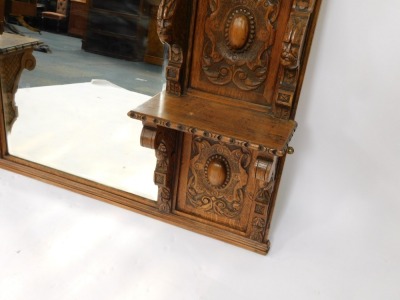A Victorian oak overmantel mirror, the pediment carved with the head of a lion and foliate scrolls, above a rectangular bevelled glass mirror surmounted and flanked by five shelves with figural or scrolling supports, panels of carved roundels foliate scro - 3