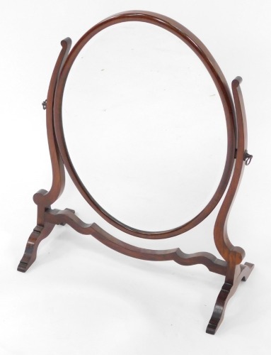 An Edwardian mahogany swing frame toilet mirror, inset oval bevelled glass, within a show frame, 56cm high, 46cm wide.