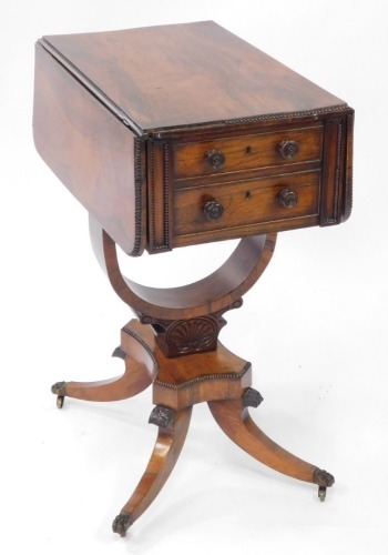 A Regency rosewood drop leaf work table, with two frieze drawers, raised on a U shaped support, over a quatrefoil base above out swept legs, brass paw capped on castors, 75cm high, 36cm wide, 72.5cm extended, 56cm deep.