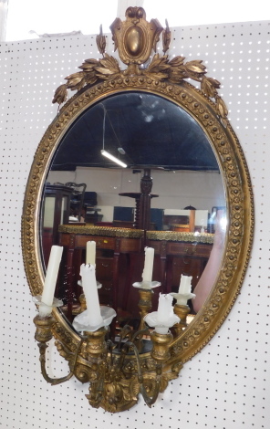 A Victorian gilt wood and gesso oval girandole, with shield and leaf surmount, having three scrolling candle holders, 89cm high, 54.5cm wide.