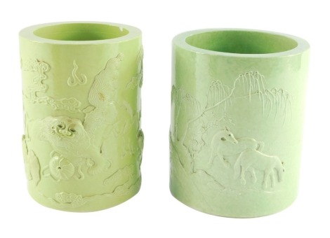 Two Chinese green glazed brush pots, of cylindrical form, one moulded with horses in a landscape, bears four character mark, 13cm high, the other moulded with lion dogs and flaming pearls amongst clouds, bears four character mark, 14cm high. (2)