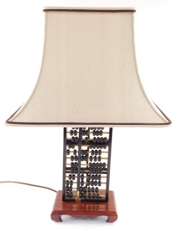 A Chinese abacus form table lamp, raised on a wooden base, with shade, 59cm high.