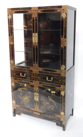 A Chinese black and gilt lacquer display cabinet, with glass panelled doors and sides enclosing two glass shelves, above a pair of drawers over cupboard doors painted with panels of birds and blossom, raised on bracket feet, 173cm high, 91cm wide, 46cm de