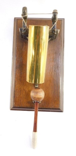 An early 20thC wall mounted gong, formed as a shell case, oak mounted, with beater, 28cm high.