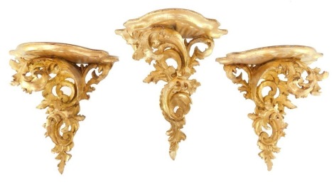 A pair of rococo style gilt wood wall shelves, of serpentine form, raised on fillet scroll supports, 34cm high., together with a smaller wall shelf, 46cm high. (3)