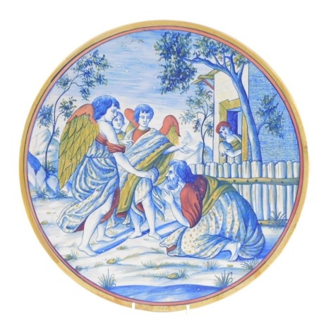 An Italian late 19thC maiolica charger, painted with a kneeling figure supplicating himself before three angels, within a landscape, 41cm diameter.