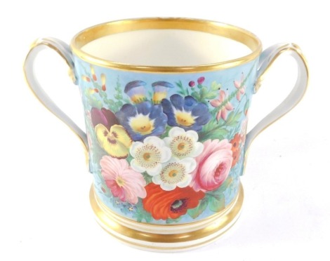 A Staffordshire mid 19thC porcelain loving cup, painted with flowers against a turquoise ground, within gilt bands, 14.5cm high.