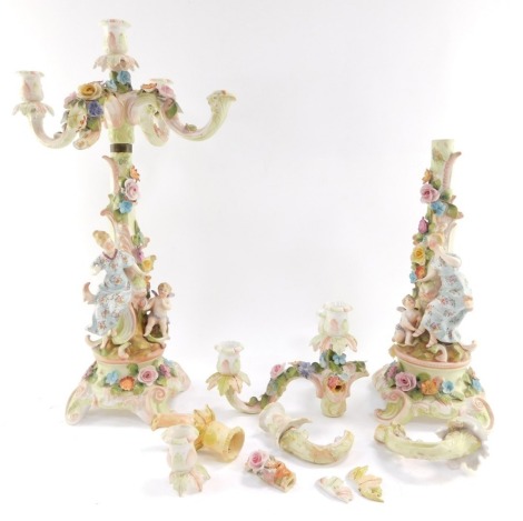 A pair of continental late 19thC porcelain candelabrum, of four branch form, encrusted with flowers, the stem surmounted with a female figure and a cherub, raised on a rococo scroll base, 49cm high. (AF)