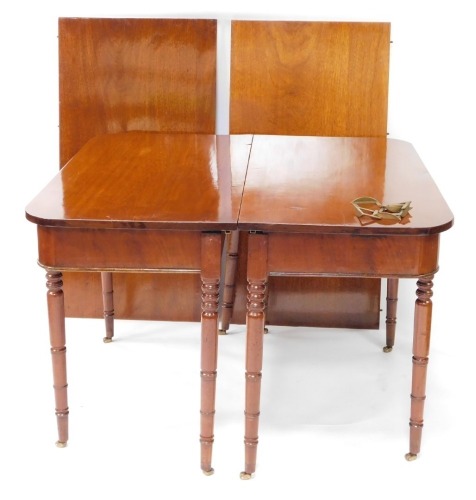 A George IV mahogany D end dining table, with two additional leaves, raised on turned legs, brass capped on castors, 77cm high, 118.5cm wide, 235cm extended, 56.6cm deep.