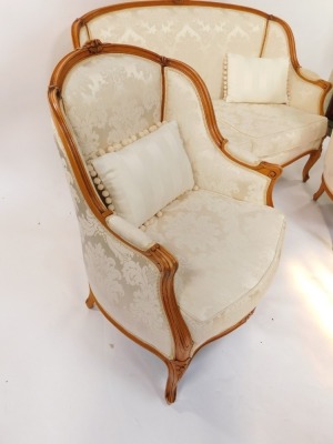 A French Louis XVI style beech wood two seater canape, with a carved show frame, pale gold fabric, floral patterned overstuffed back and loose cushion seats, raised on cabriole legs, 139cm wide, together with a pair of matching fauteuil. (3) - 2