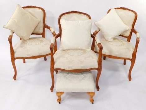 A set of three Louis XVI style pale stained oak carver chairs, with pale gold and overstuffed floral fabric, raised on cabriole seats, together with an associated footstool. (4)