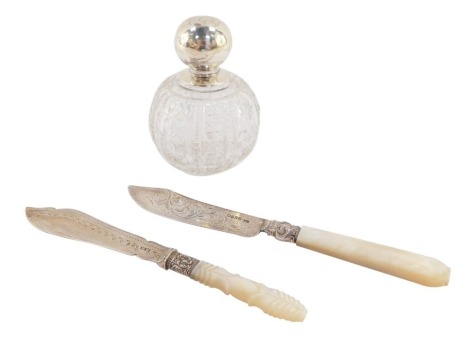 A Victorian silver butter knife, with mother of pearl handle, Birmingham 1854, further knife, Sheffield 1894, and a cut glass scent bottle, with stopper and silver lid, hallmarks worn. (AF, 3)