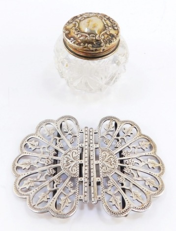 A Victorian silver nurse's belt buckle, with pieced and engraved foliate decoration, Birmingham 1900, together with a George V pressed glass ointment jar, with silver lid, embossed with flowers and rococo C scrolls, Birmingham 1914. (2)