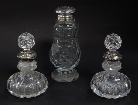 A Victorian cut glass sugar sifter, with silver lid, London 1847, together with a pair of 19thC cut glass scent bottles and stoppers, with silver collars, hallmarks worn. (3)