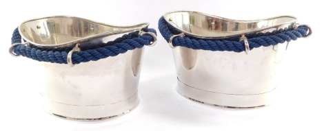 A pair of stainless steel ice baths, each cast with six rings, united by blue woven rope, 24cm high, 45cm wide.