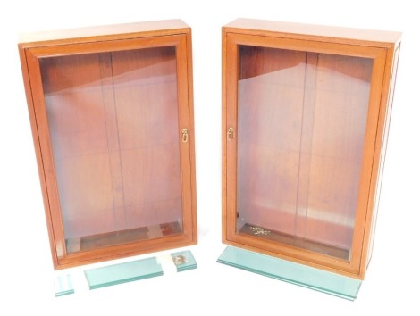 A pair of pale mahogany wall mounted display cabinets, each with a glazed door including three narrow glass shelves, 86cm high, 55.5cm wide, 14.5cm deep.