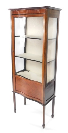 An Edwardian mahogany and line inlaid serpentine display cabinet, with a glazed door including three shelves, raised on tapering square legs and spade feet, 166cm high, 66cm wide, 34.5cm deep.