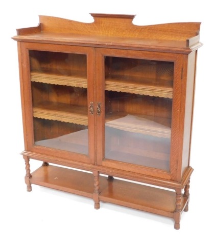 A Victorian oak glazed bookcase, with a shaped gallery over a pair of glazed doors enclosing two long shelves, above spiral twist legs, united by an under tier, 129cm high, 120cm wide, 31cm deep.