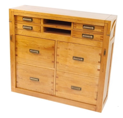 An oak desk or bureau, with a hinged top section, above an arrangement of two small drawers, and recesses above four deep filing drawers, each with brass handles, on a plinth, 101cm high, 112cm wide, 35cm deep.