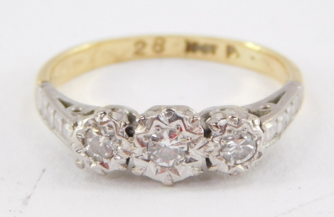 A three stone diamond ring, each round brilliant cut diamond set in raised illusion platinum setting, with rib designed shoulders on a yellow metal band stamped 18ct gold and 0.2 carats of diamonds, ring size K½, 2.5g all in.