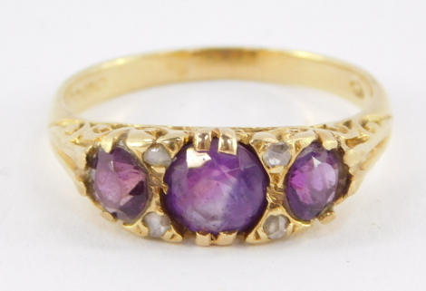 An 18ct gold and amethyst three stone ring, set with pairs of diamonds at intervals, size R, 4.8g.