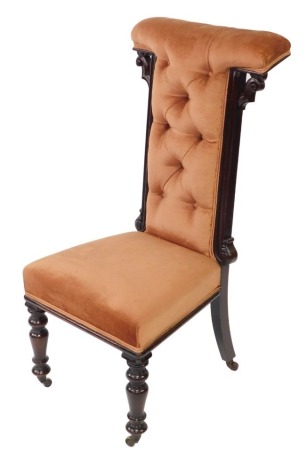 A Victorian rosewood prie dieu chair, upholstered in button back peach velour, raised on turned legs, on brass castors.