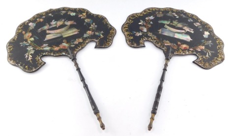 A pair of early 19thC papier mache hand held candle screens, with mother of pearl inlay, decorated with doves within a surround of flowers, turned wooden handles, 39cm high.