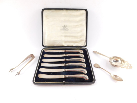 A George VI silver tea strainer, Birmingham 1937, George V sugar nips, Birmingham 1923, George V commemorative teaspoon, HH Sports 1933, London 1933, 2.2toz, together with a set of six George V silver pistol handled cake knives, cased, Sheffield 1916.