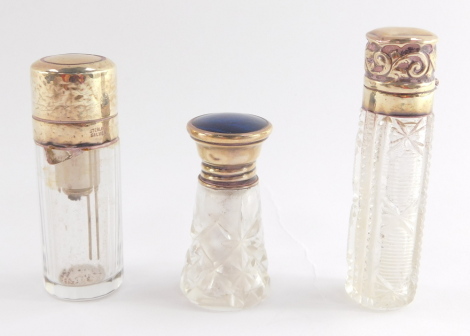 An Edward VII cut glass scent bottle, with silver mounted hinged lid, embossed with foliate scrolls, Birmingham 1901, George V cut glass bottle with silver screw lid inset blue butterfly wing, Birmingham 1925, and a cut glass atomiser with silver mount an