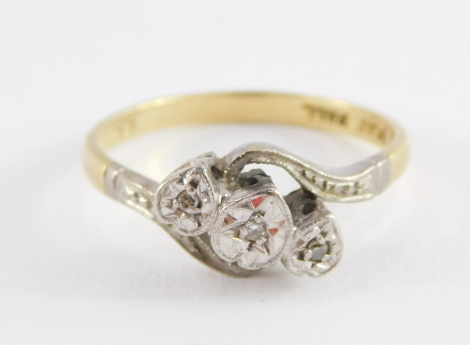 An 18ct gold and diamond three stone ring, illusion set in a crossover design, size N, 2.6g.