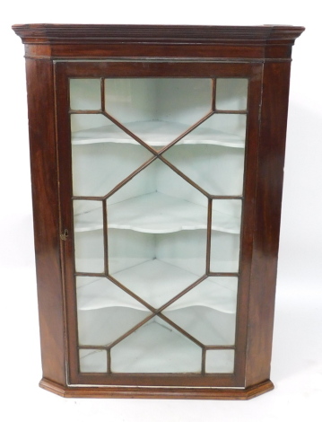 A Georgian mahogany wall hanging corner cupboard, the out swept pediment over an astragal glazed door, enclosing three shaped shelves, raised on a plinth base, 201cm high, 84cm wide.