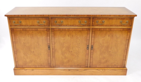 A Reprodux burr oak and cross banded sideboard, of three drawers over cupboard doors, raised on a plinth base, 84cm high, 154cm wide, 42cm deep.