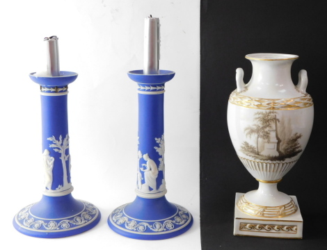 A pair of Wedgwood late 19thC dark blue Jasper candlesticks, sprigged with classical figures, 22cm high, together with a German 19thC porcelain vase, of twin handled baluster form, decorated en grisaille, with a memorial, painted marks, 25cm high. (AF)