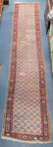 A Caucasian cream ground runner, decorated with floral motifs within geometric borders, 532cm x 108cm.