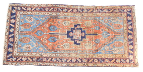 A Caucasian red and blue ground rug, decorated with floral and foliate motifs, within repeating geometric borders, 182cm x 89cm.