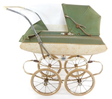 A Tri-ang coach built doll's pram, with a cream and green body, white interior and green folding hood, 81cm wide.