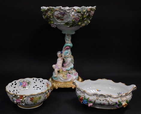 A continental porcelain comport, moulded with a putto, encrusted with flowers and printed with reserves of floral sprays, on a fluted brass circular base, on scroll feet, 37cm high, together with a Dresden porcelain bowl, of boat shaped form, encrusted an