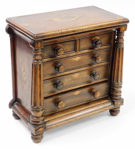 A Victorian apprentice chest of drawers, with two short and three long drawers, with columned supports on bun feet, and diamond inlay, probably Scottish, 39cm high, 39cm wide, 30cm deep.