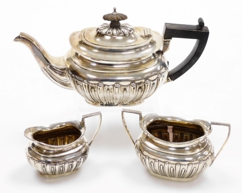 A Victorian silver three piece tea service, with ebonised handle and fluted body comprising teapot, milk jug and sugar bowl, Chester 1900, 12¼oz gross.