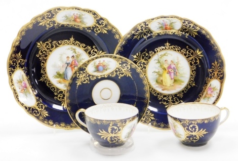 Continental cabinet porcelain, comprising two plates, two cups and one saucer, all with hand painted reserve of lovers in a landscape, with blue de roi border and gilding, various marks. (5)